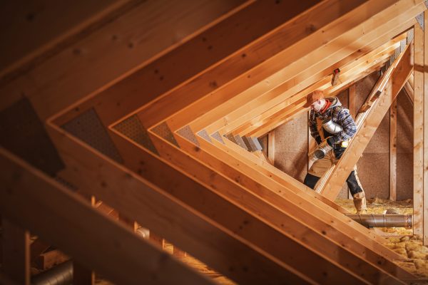 Professional Contractor Installing Ventilation Ducts in the Roof Part of Freshly Built Residential House.