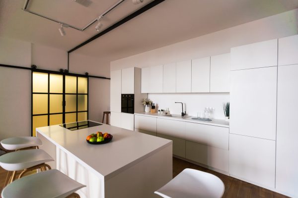 Kitchen in new luxury home with quartz waterfall island, hardwood floors, dark wood cabinets, and stainless steel appliances.